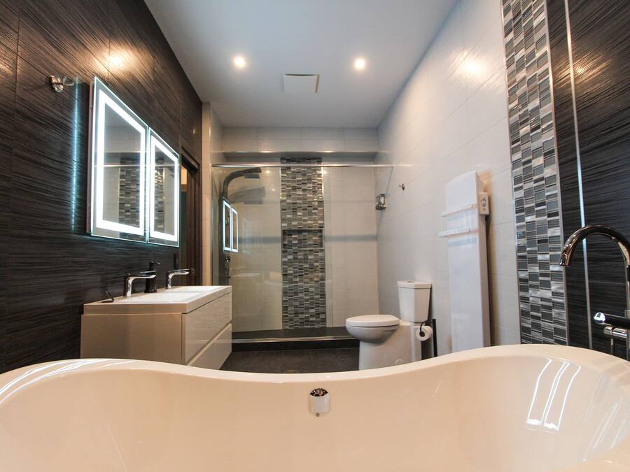 A modern bathroom with a freestanding bathtub, a glass-enclosed shower, and a vanity with a mirror.