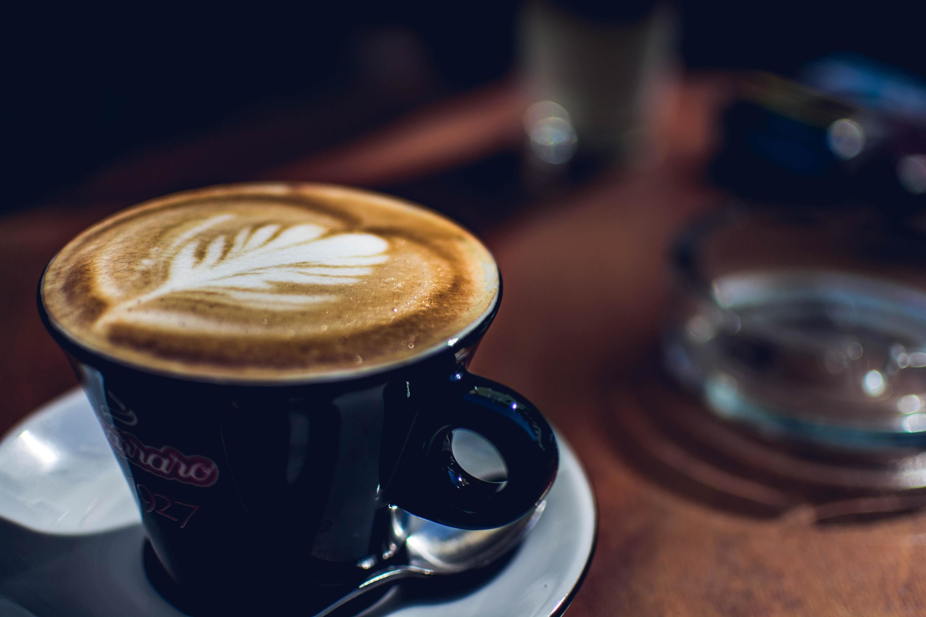 A cup of coffee with a latte art design on a saucer.
