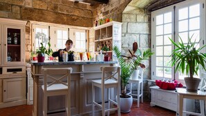 Una cocina con una isla central, armarios blancos y una pared de piedra.
