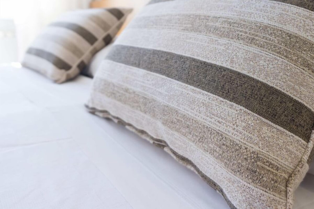 Una cama con almohadas a rayas y un cabecero blanco.