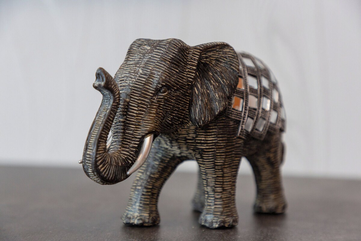 Una pequeña figurita de elefante con textura sobre un fondo oscuro.