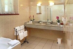 Une salle de bain avec deux lavabos, un grand miroir et un porte-serviettes avec des serviettes blanches.