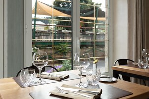 Una mesa de comedor con copas de vino, cubiertos y una servilleta, con vistas a un patio exterior a través de una ventana.