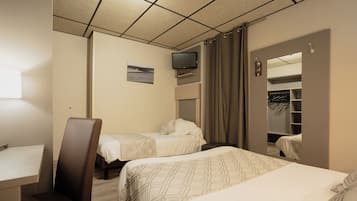 Een hotelkamer met twee bedden, een bureau, een stoel, een televisie en een kledingkast.