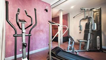 Une salle de sport équipée de matériel d’exercice, notamment un tapis de course, des appareils de musculation et un vélo d’appartement.