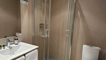 A modern bathroom with a glass-enclosed shower, a white sink, and a toilet.
