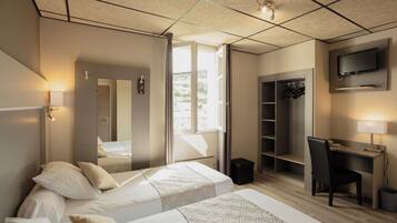 A hotel room with two beds, a desk, a TV, and a wardrobe.