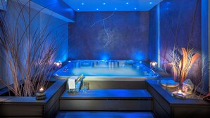 A modern spa room with a hot tub, blue ambient lighting, and decorative plants. - Hotel Family and Spa (Meyrueis)