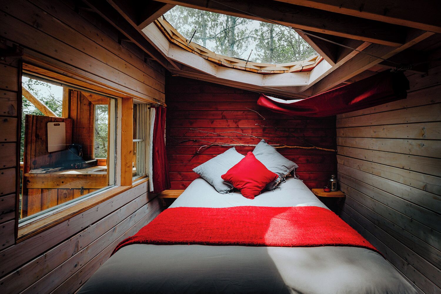 Una habitación pequeña y acogedora con cama, tragaluz y ventana.