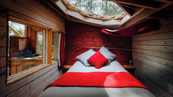 Una habitación pequeña y acogedora con cama, tragaluz y ventana.