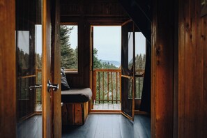 Uma cabana de madeira com um banco e vista para a floresta.