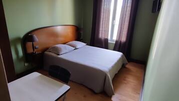 Une chambre d’hôtel équipée d’un lit, d’un bureau, d’une chaise et d’un ventilateur de plafond.