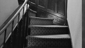 A staircase with a patterned carpet and metal handrails, leading to a wooden door with a sign above it. - Hôtel Saint-Pierre (Villedieu-les-Poêles-Rouffigny)