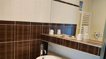 A modern bathroom with a large sink, a mirror, and a towel rack.