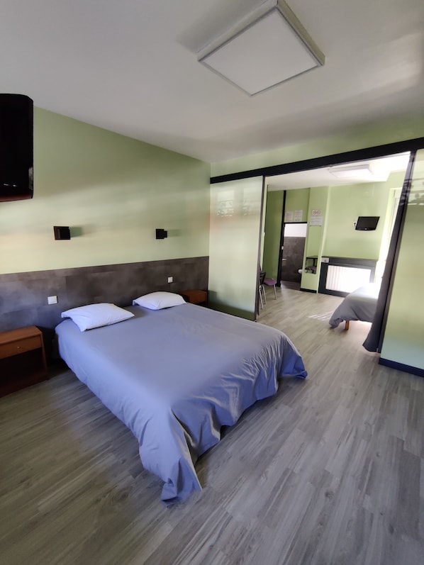 A hotel room with a large bed, a small bedside table, a mirror, and a sliding door leading to a bathroom. - Hôtel Saint-Pierre (Villedieu-les-Poêles-Rouffigny)