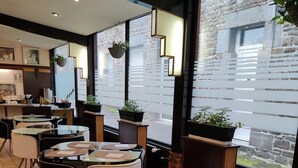 A modern cafe with hexagonal tiled flooring, round tables with black chairs, and large windows with a view of the street. - Hôtel Saint-Pierre (Villedieu-les-Poêles-Rouffigny)