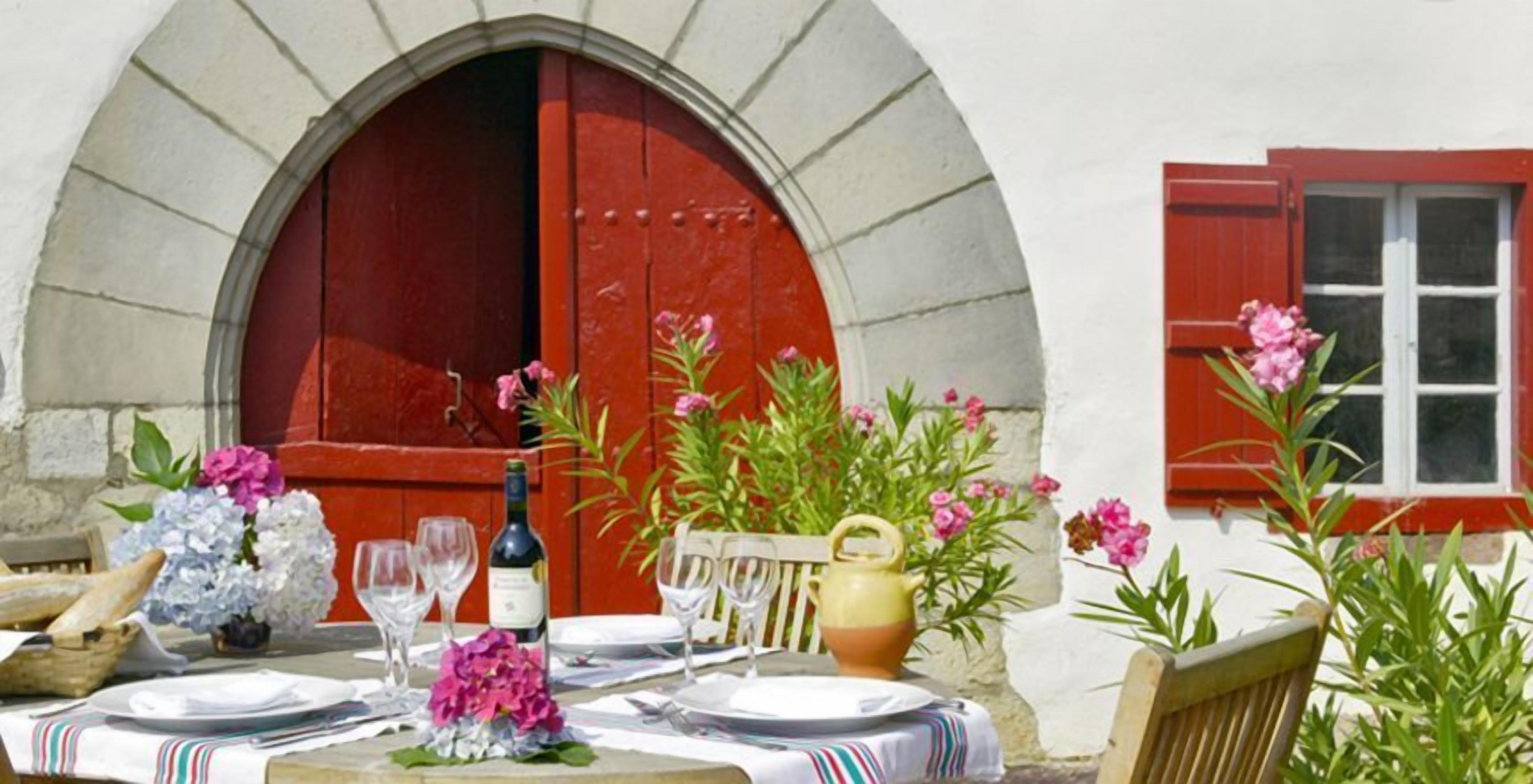 Un montaje para comer al aire libre con una mesa para dos, una botella de vino y diversas flores.