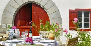 An outdoor dining setup with a table set for two, a bottle of wine, and various flowers.