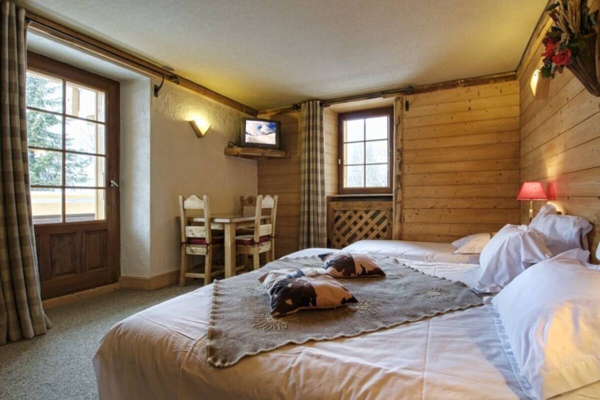 Um quarto aconchegante com uma cama grande, televisão e uma pequena mesa com cadeiras.