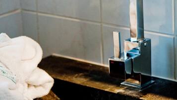 Un lavabo de salle de bain avec un robinet moderne, une serviette et un mur carrelé.