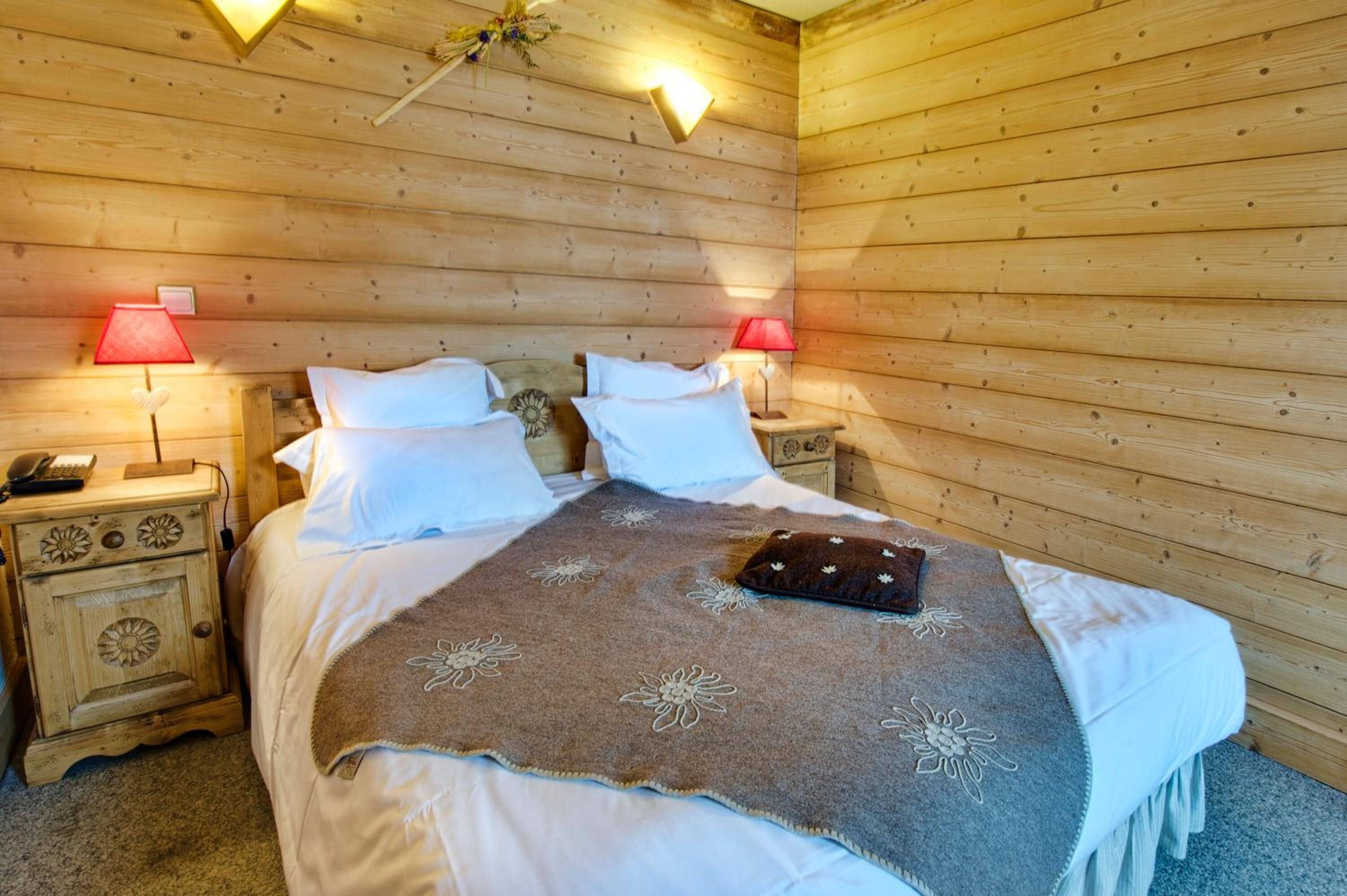 Une chambre dans une cabane en bois, avec un lit, deux tables de chevet et deux lampes.