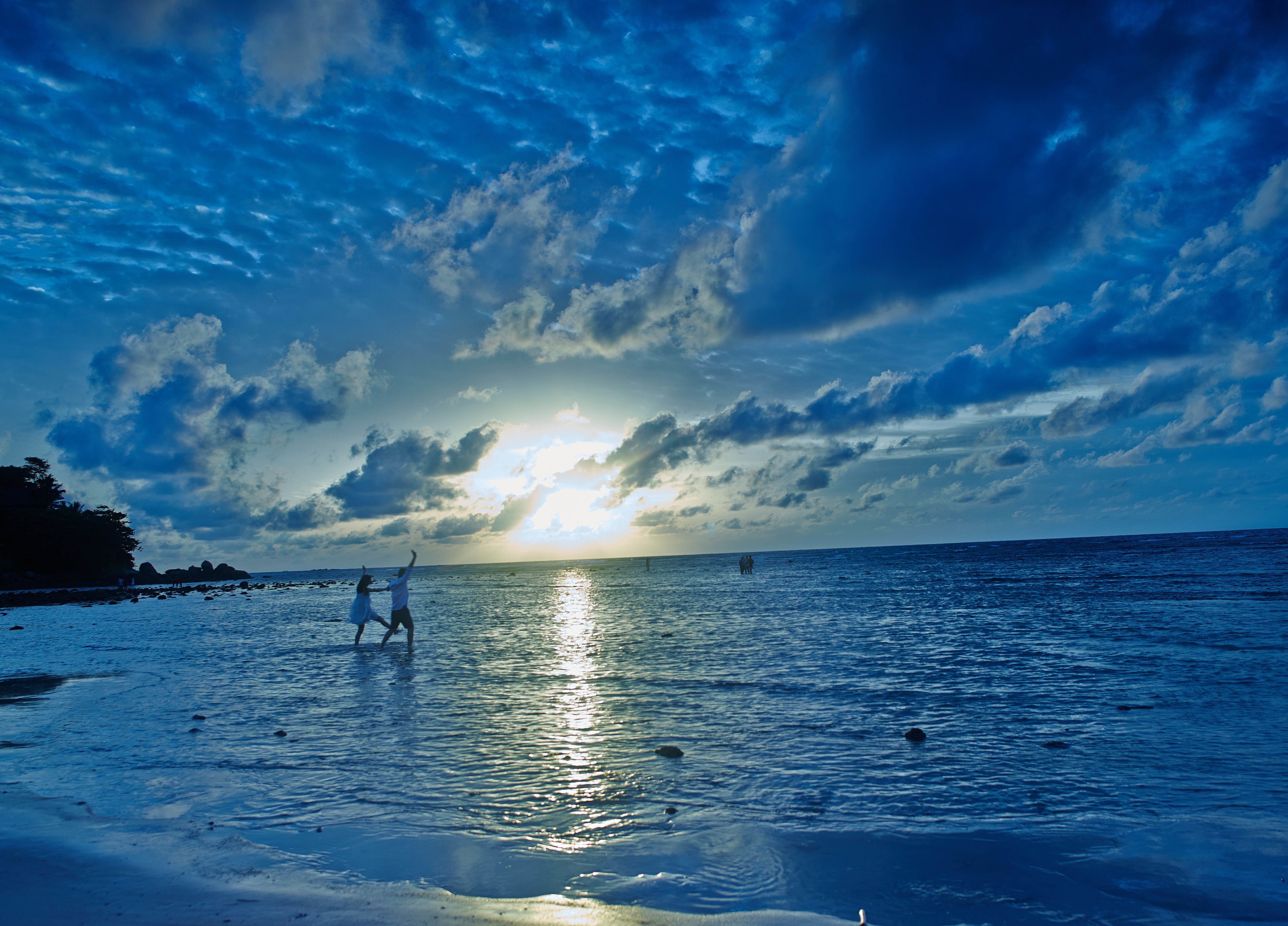A beach scene with a sunset, calm sea, and rocky coastline.