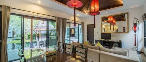 Un espacio moderno de sala con una mesa de comedor, sofás y televisor. Amplias ventanas ofrecen vistas al exterior.