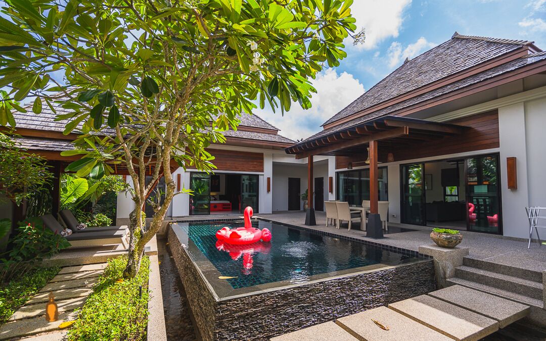 A modern house with a swimming pool, outdoor seating, and lush greenery.