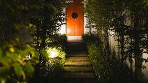 A pathway leading to a wooden door surrounded by greenery. - The Bell Pool Villa Resort (Kamala)