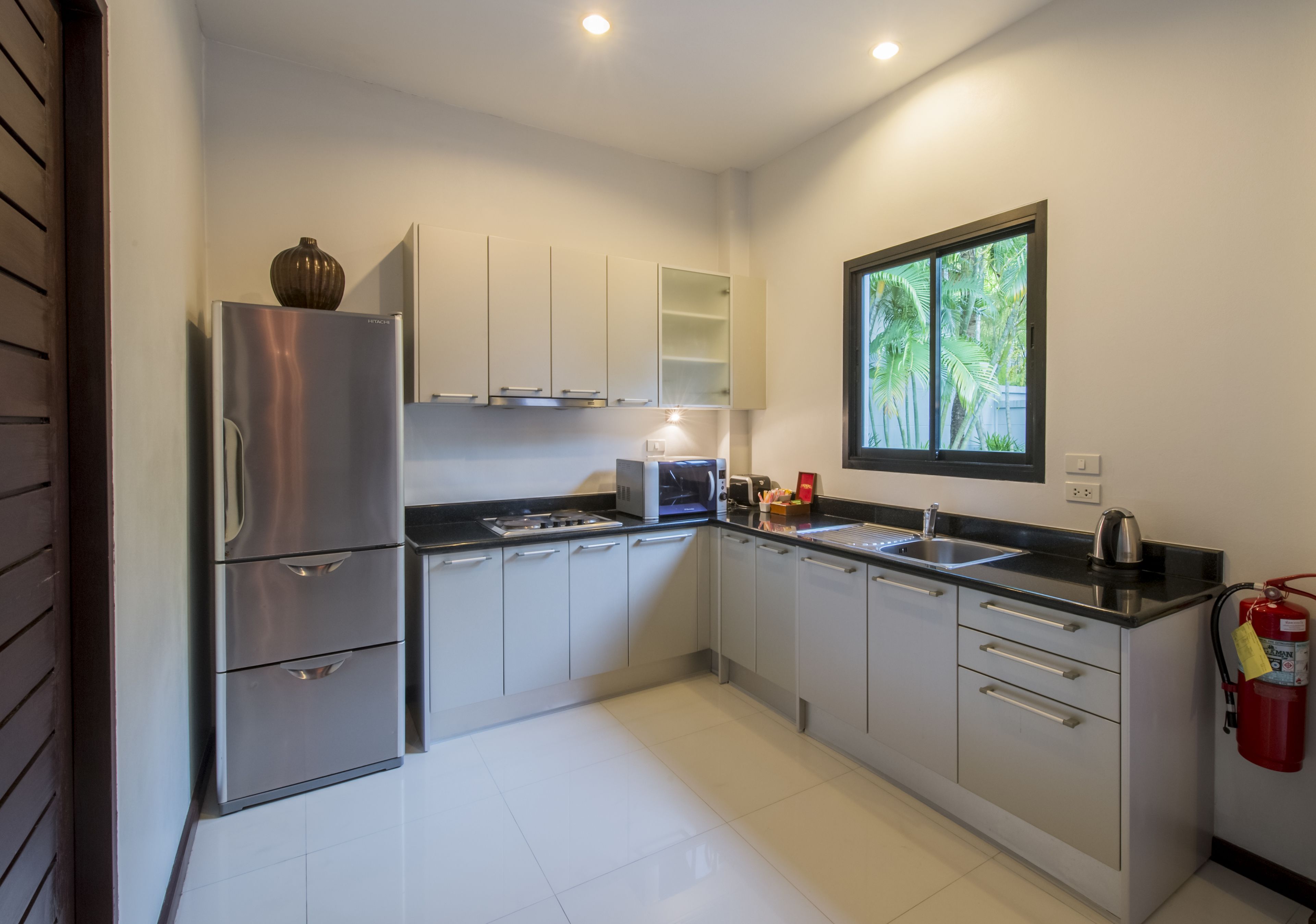 Una cocina moderna con electrodomésticos de acero inoxidable, armarios blancos y un ventanal con vistas a la vegetación.