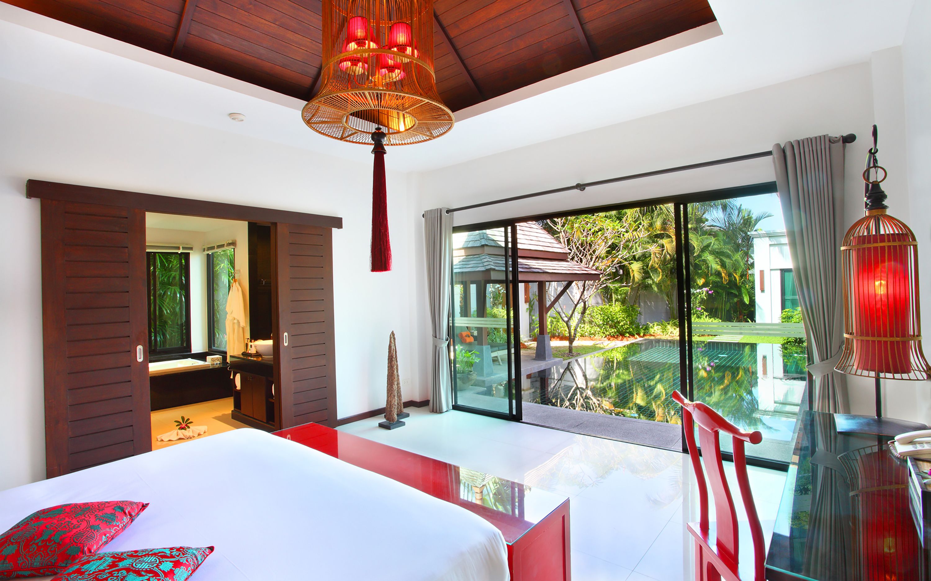 Un dormitorio moderno con una cama grande, un ventanal de vidrio que da a un balcón y vistas al exterior.
