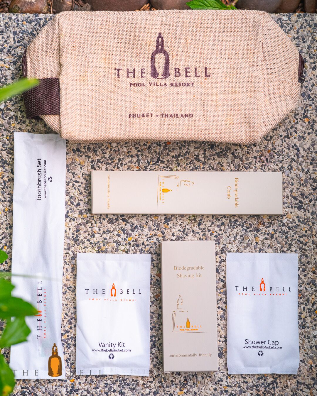 A collection of The Bell Pool Villa Resort branded items including a toothbrush set, vanity kit, biodegradable shaving kit, and shower cap.