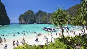 A beach with clear turquoise water, boats, and people enjoying the beach. - The Bell Pool Villa Resort (Kamala)