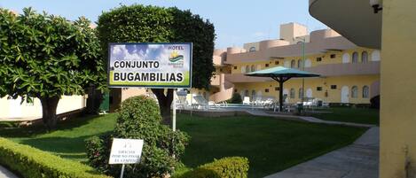 A hotel sign with a pool area in the background.
