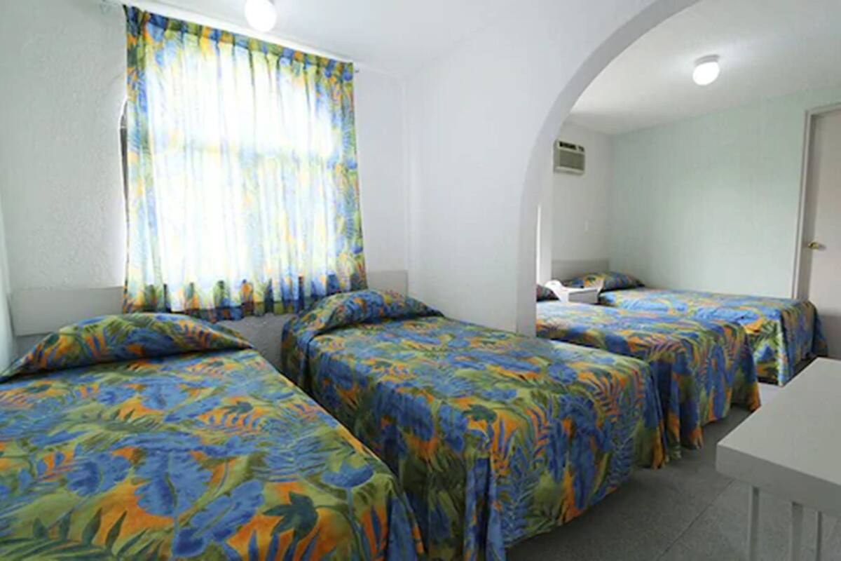 A room with two single beds, a small table, and a window with curtains.