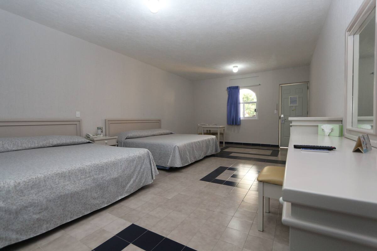 A room with two single beds, a desk, and a chair.