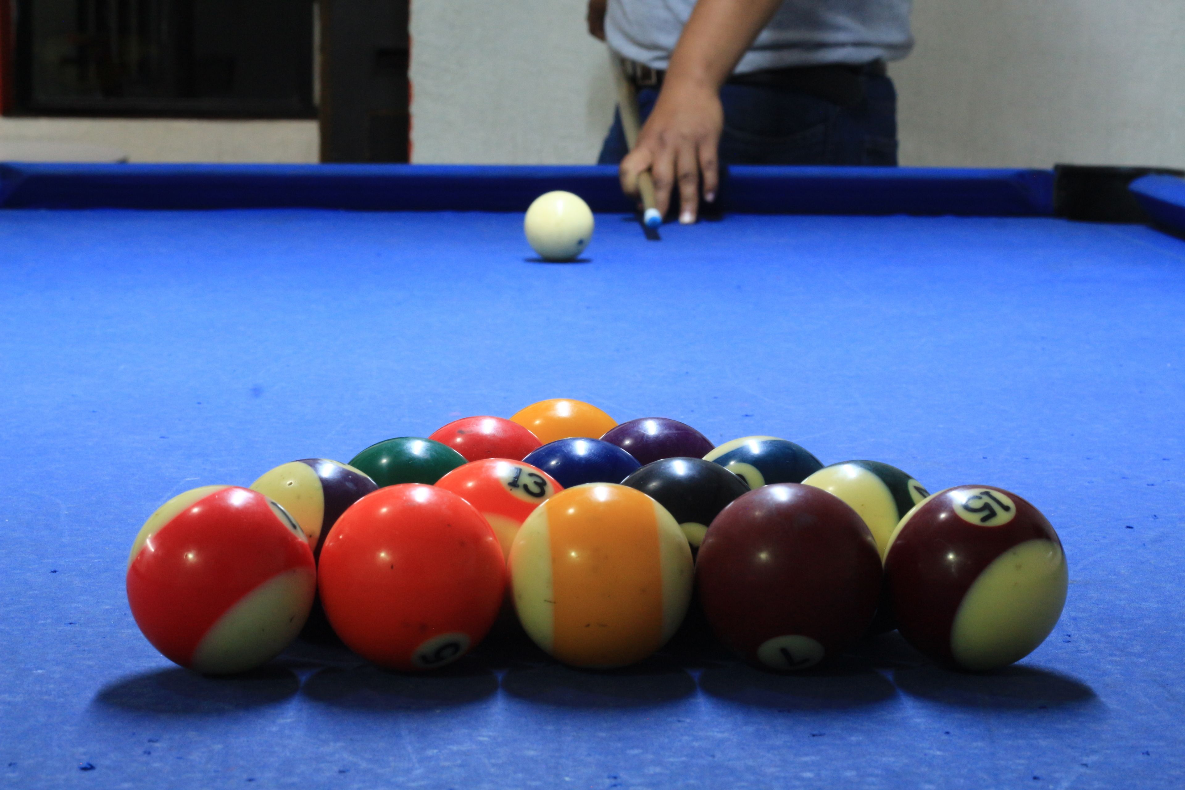 A pool table with a variety of colored balls and a person playing.