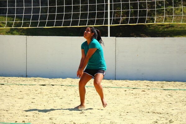 Un terrain de volley-ball avec un filet, du sable et un mur en arrière-plan.