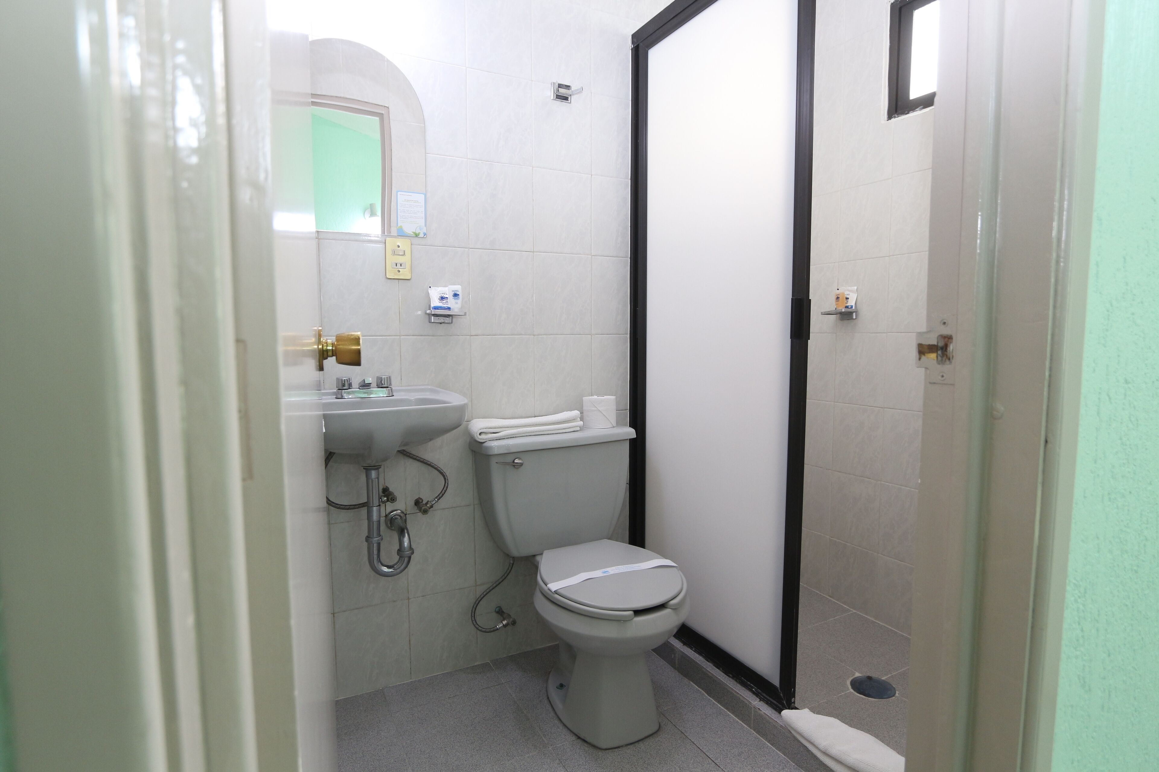 A small, clean bathroom with a toilet, sink, and shower.
