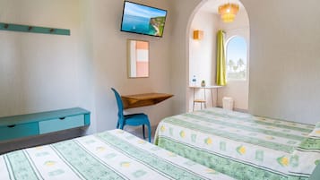 Un dormitorio con cama, escritorio, silla, televisor y ventana con cortinas.