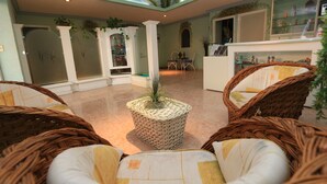 A spacious lobby with wicker furniture, a central plant, and a ceiling mural. - Dorados Conventions & Resort (Yautepec)