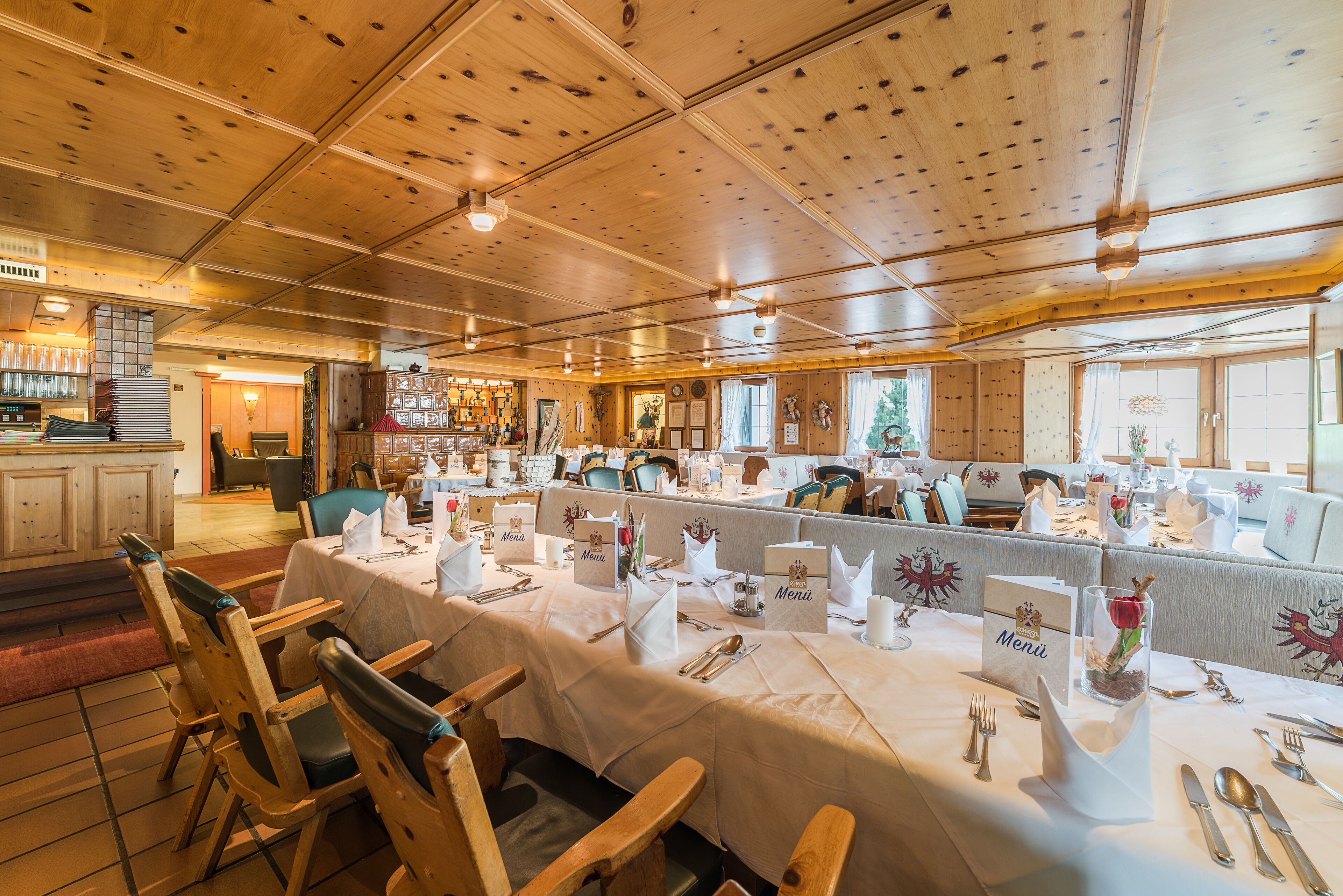 Un restaurant au plafond et aux murs en bois, avec des tables recouvertes de nappes blanches et des chaises en bois.