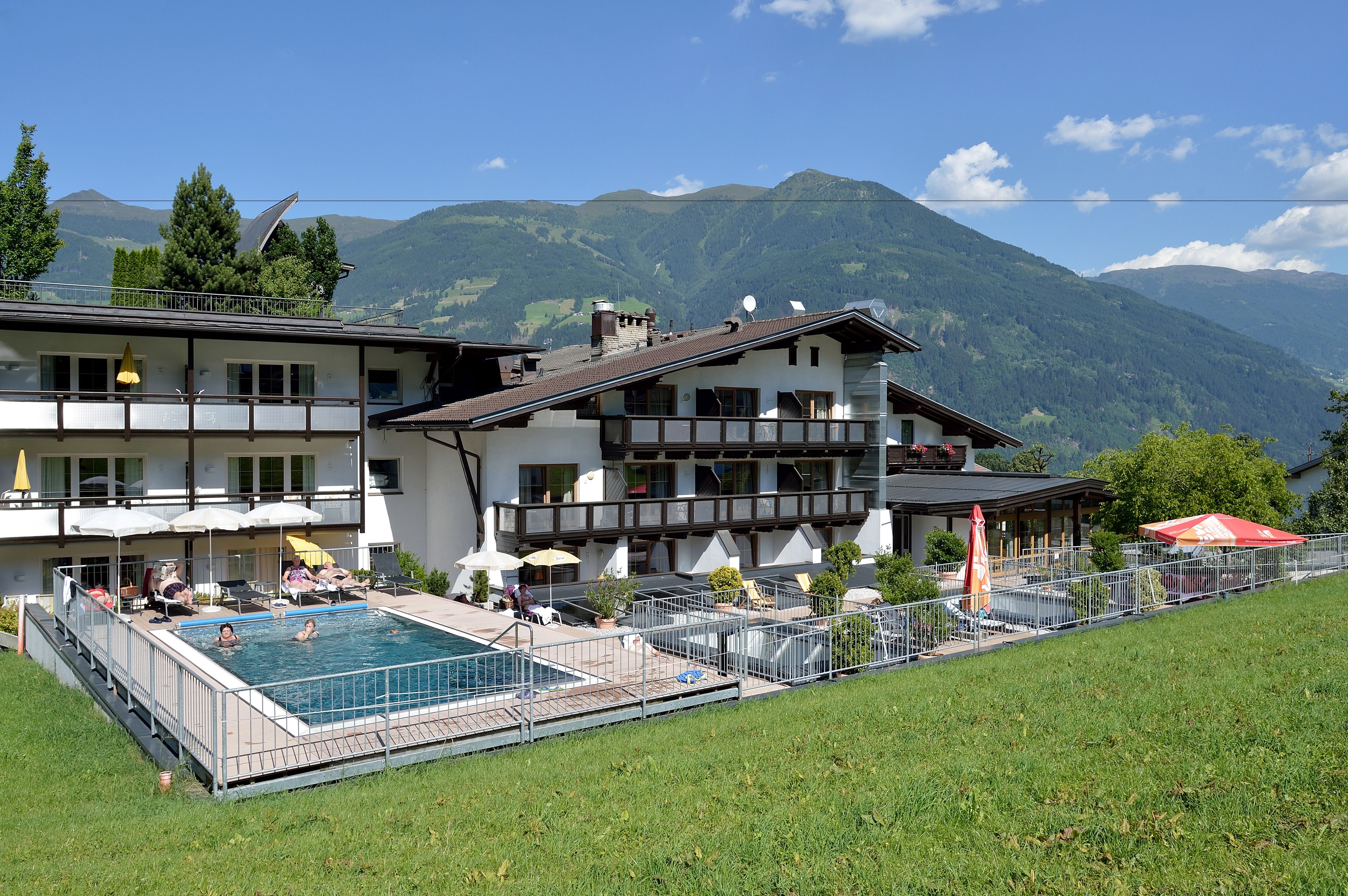 Un hotel con piscina, mobiliario exterior y vistas a la montaña.