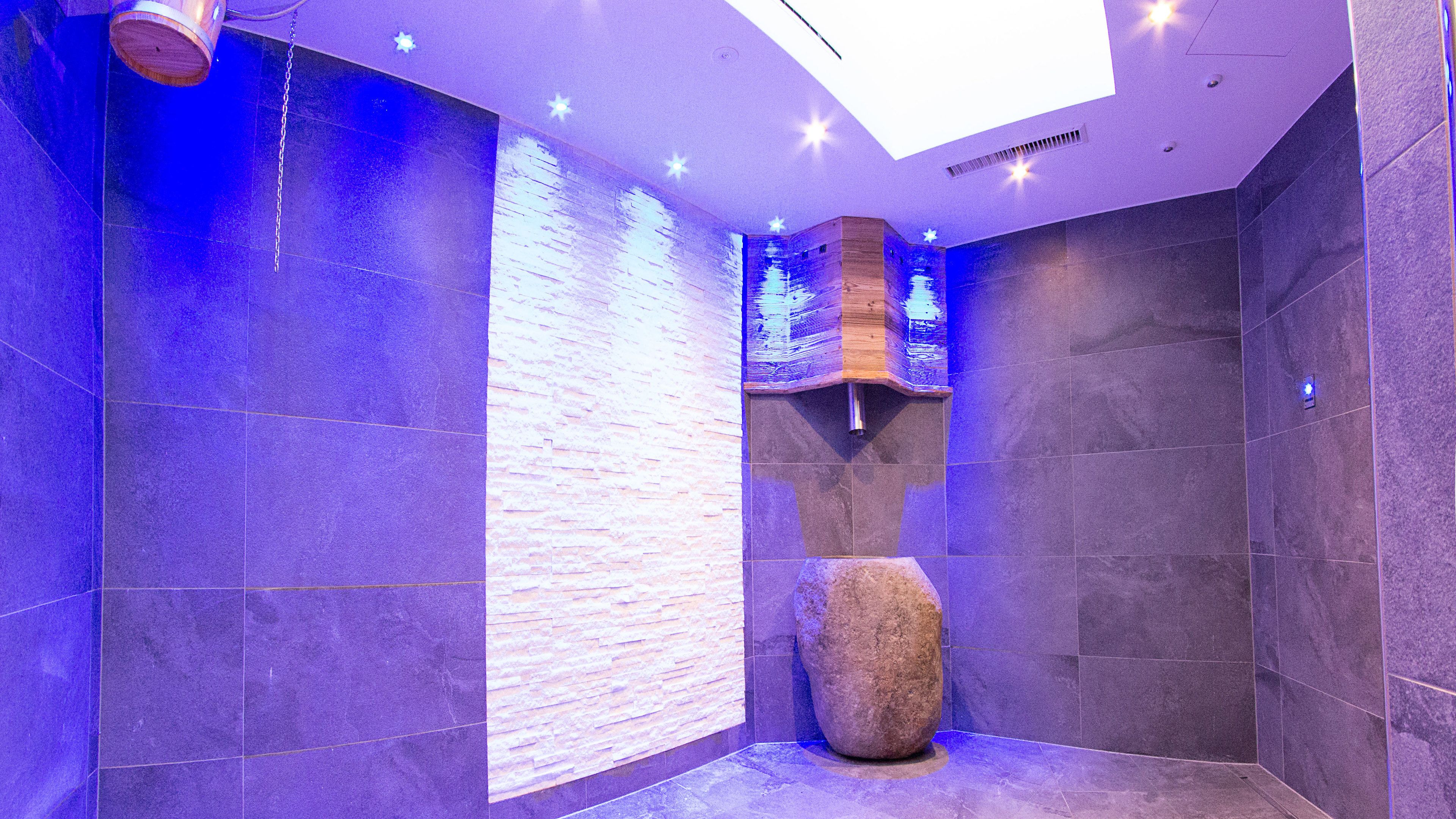 A modern bathroom with a stone wall, a large rock centerpiece, and a skylight.