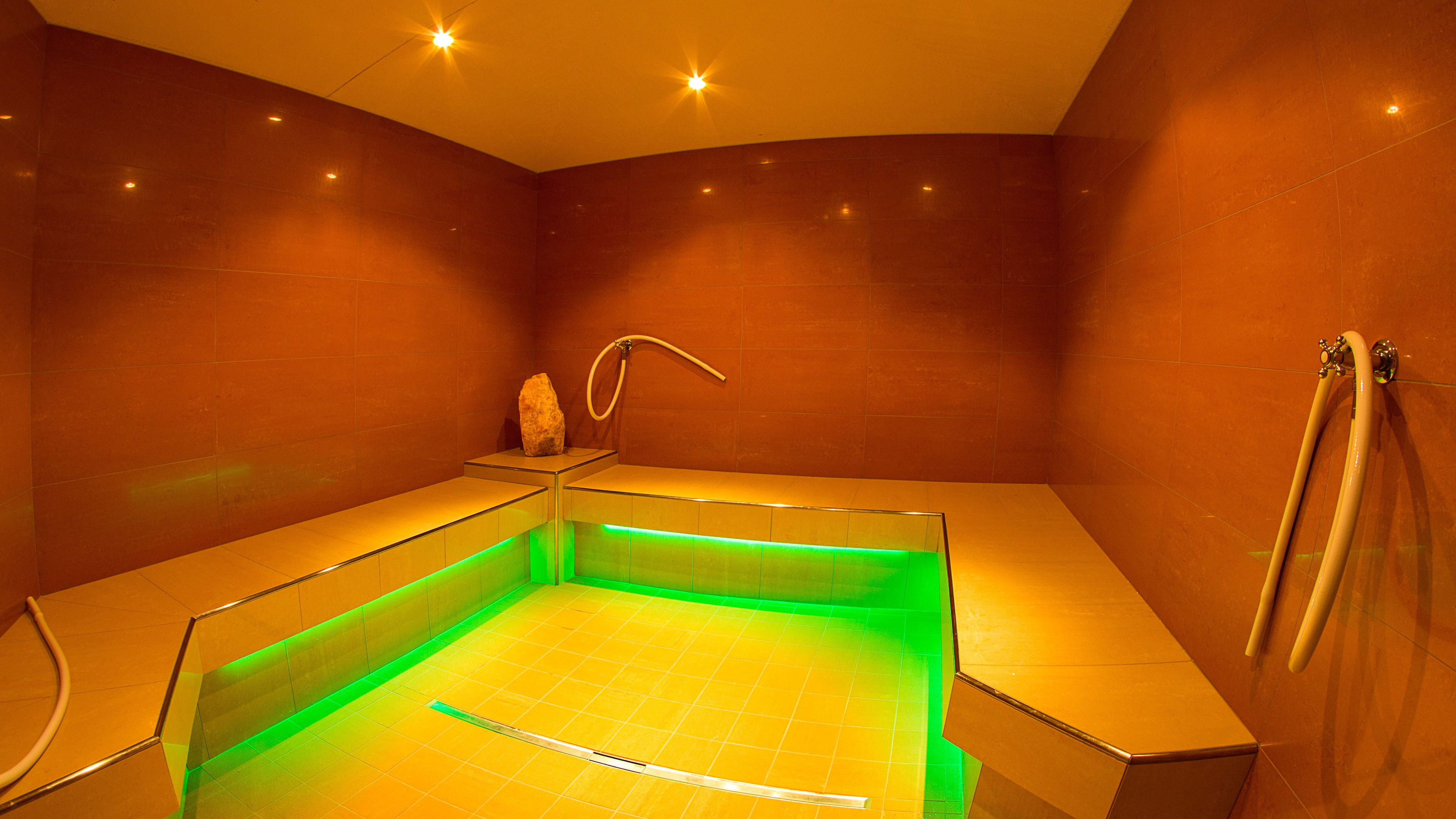 Un moderno spa con suelo radiante, una escultura de piedra y zona de ducha.