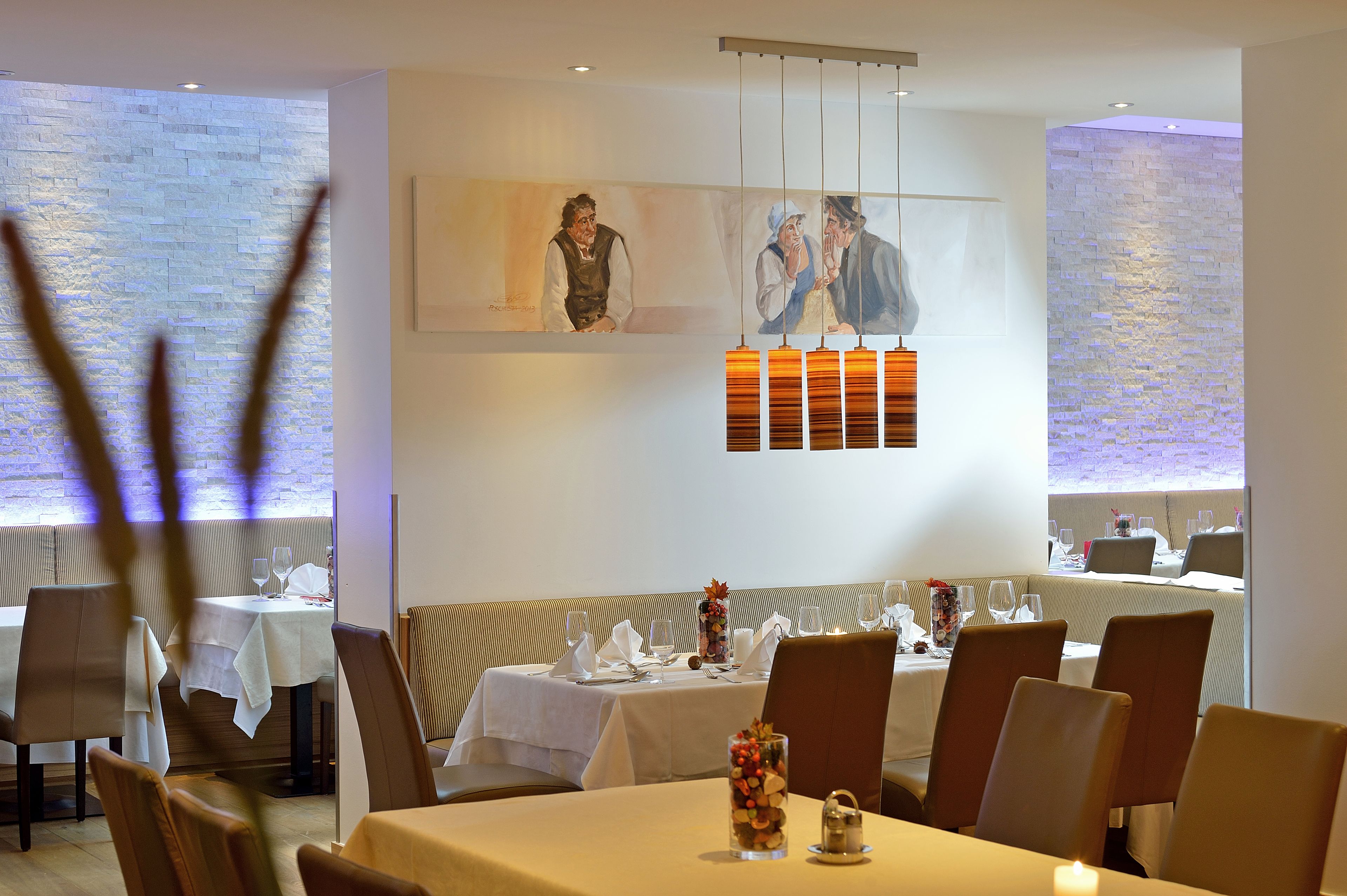 Un restaurante con mesas dispuestas para comer, un banco y una pared con pinturas.