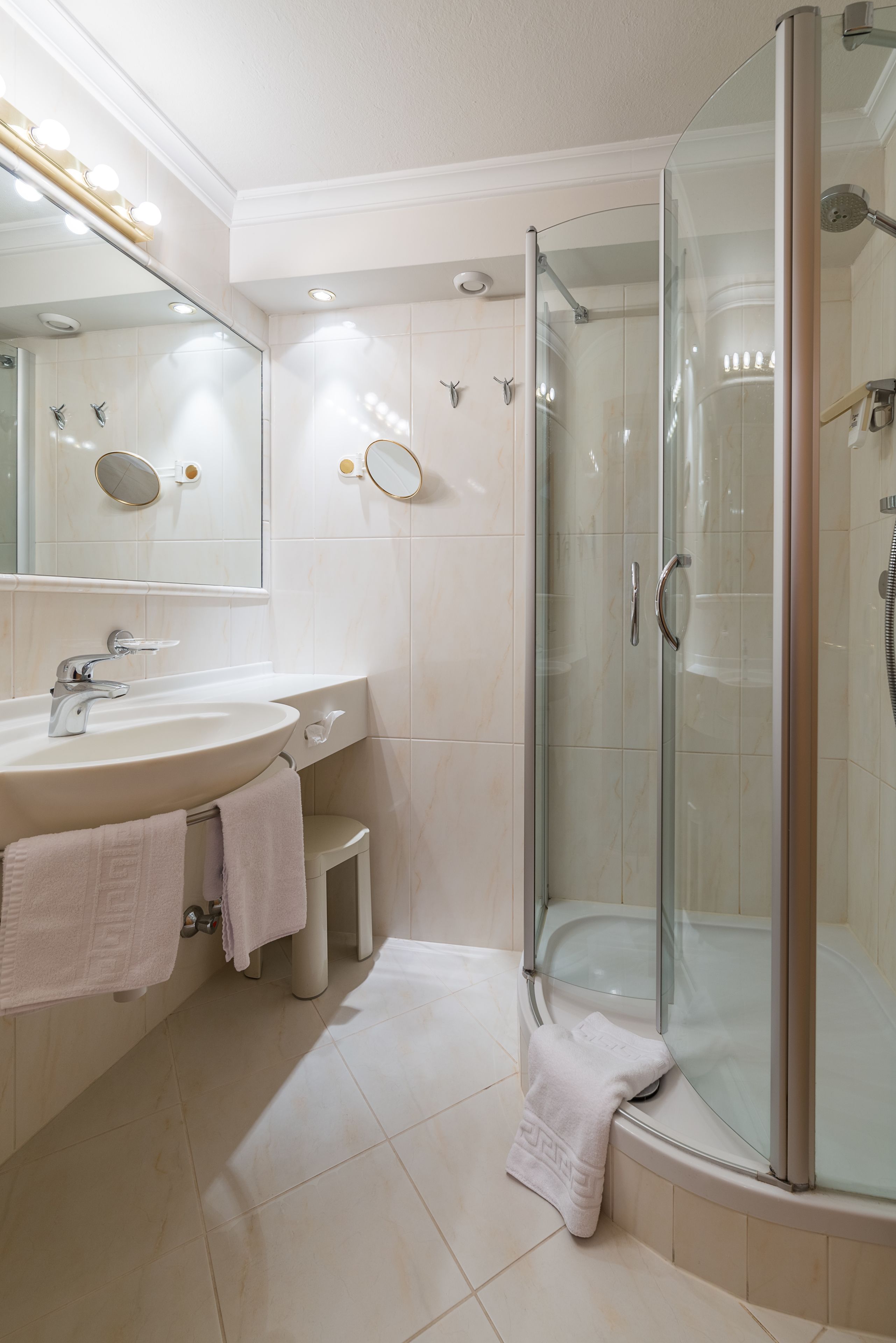 Un baño moderno con ducha de mampara de vidrio, un lavabo con espejo y tocador.