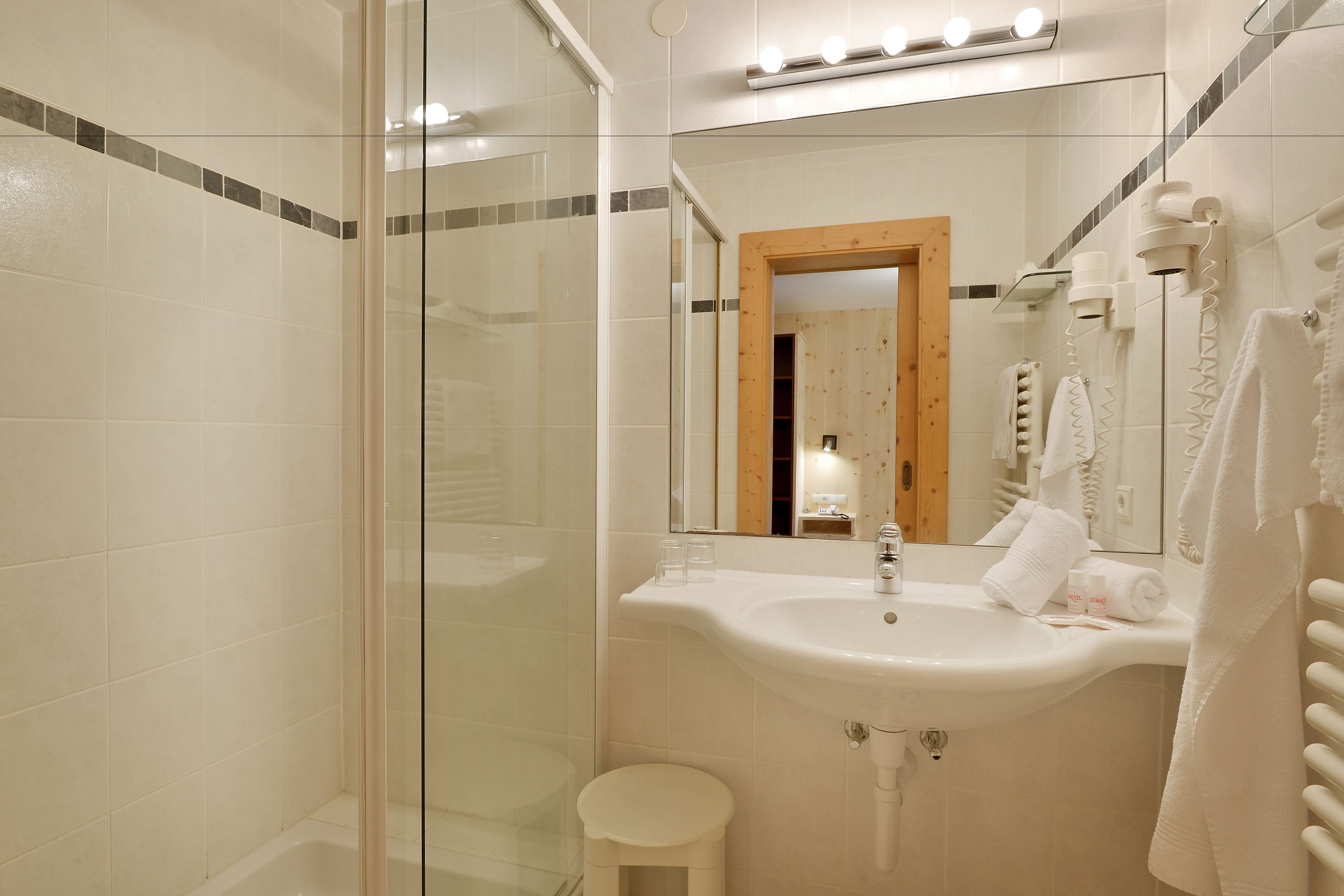 Une salle de bain avec une douche à parois de verre, un lavabo avec un miroir et un porte-serviettes.