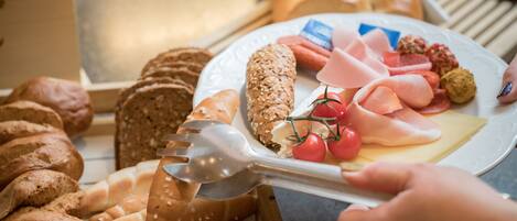 Una variedad de panes y quesos en un plato, con un tenedor en uso.