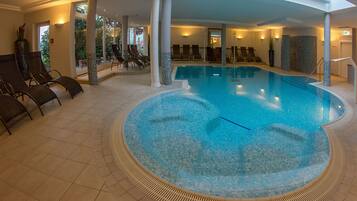 Ein Hallenbad mit Liegestühlen und Fliesenboden.